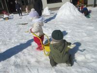 手押し車に雪を入れて運ぶ子ども